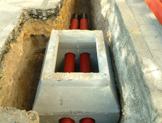 Obras de una arqueta abierta en el suelo mostrando los cables de red eléctrica